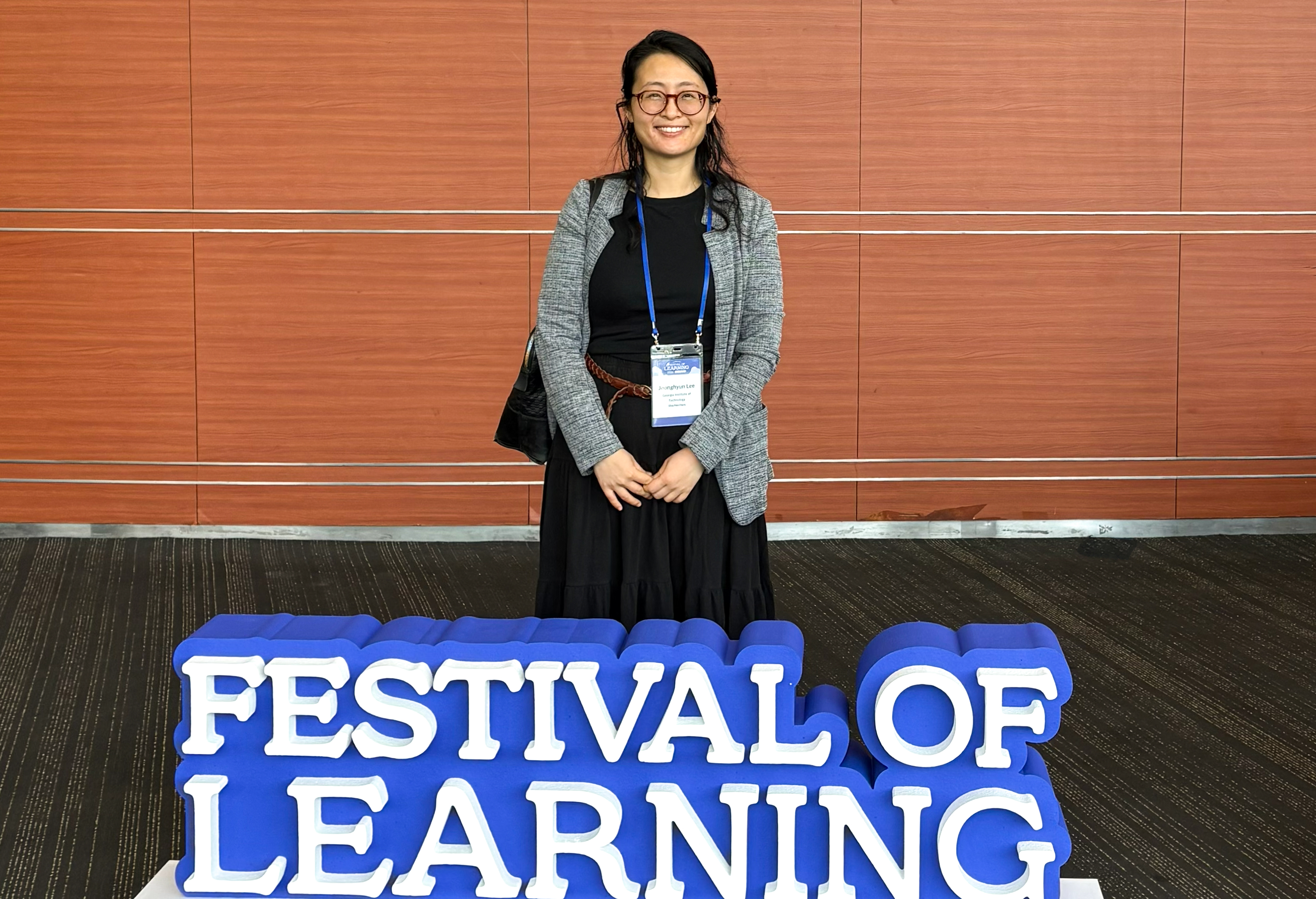 Jonna Lee standing behind a Festival of Learning sign in Seoul, Korea.